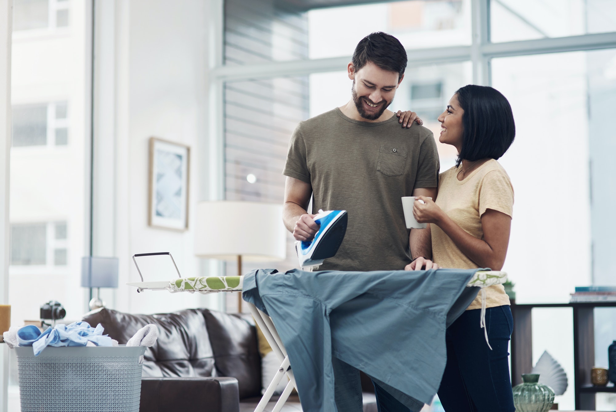Shot of a happy young couple ironing freshly washed laundry together at home